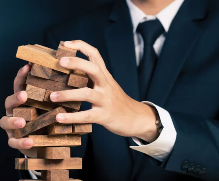 Business man's handles juggling a toppling Jenga puzzle.