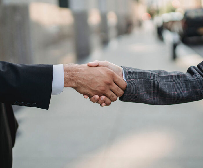 Close up of two business people shaking hands on a sidewalk in New York City.